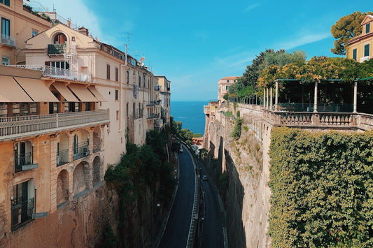 a street with a car driving down it next to a cliff