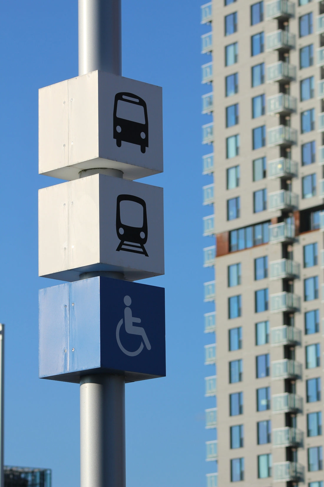 Public transport and accessibility signs near a tall building