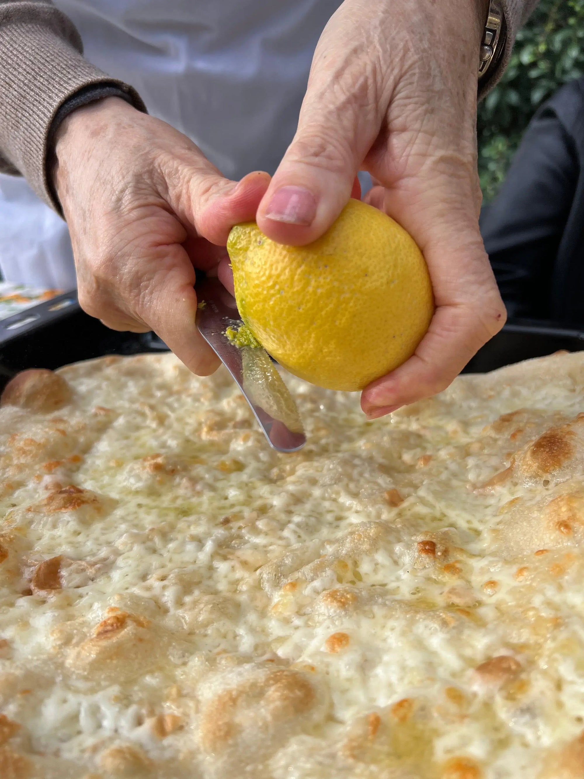 Things to do in Sorrento: squeezing lemon on fresh pizza during local cooking class.