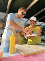 Participants enjoying a private pizza making class in Sorrento, preparing dough under a sunlit canopy.