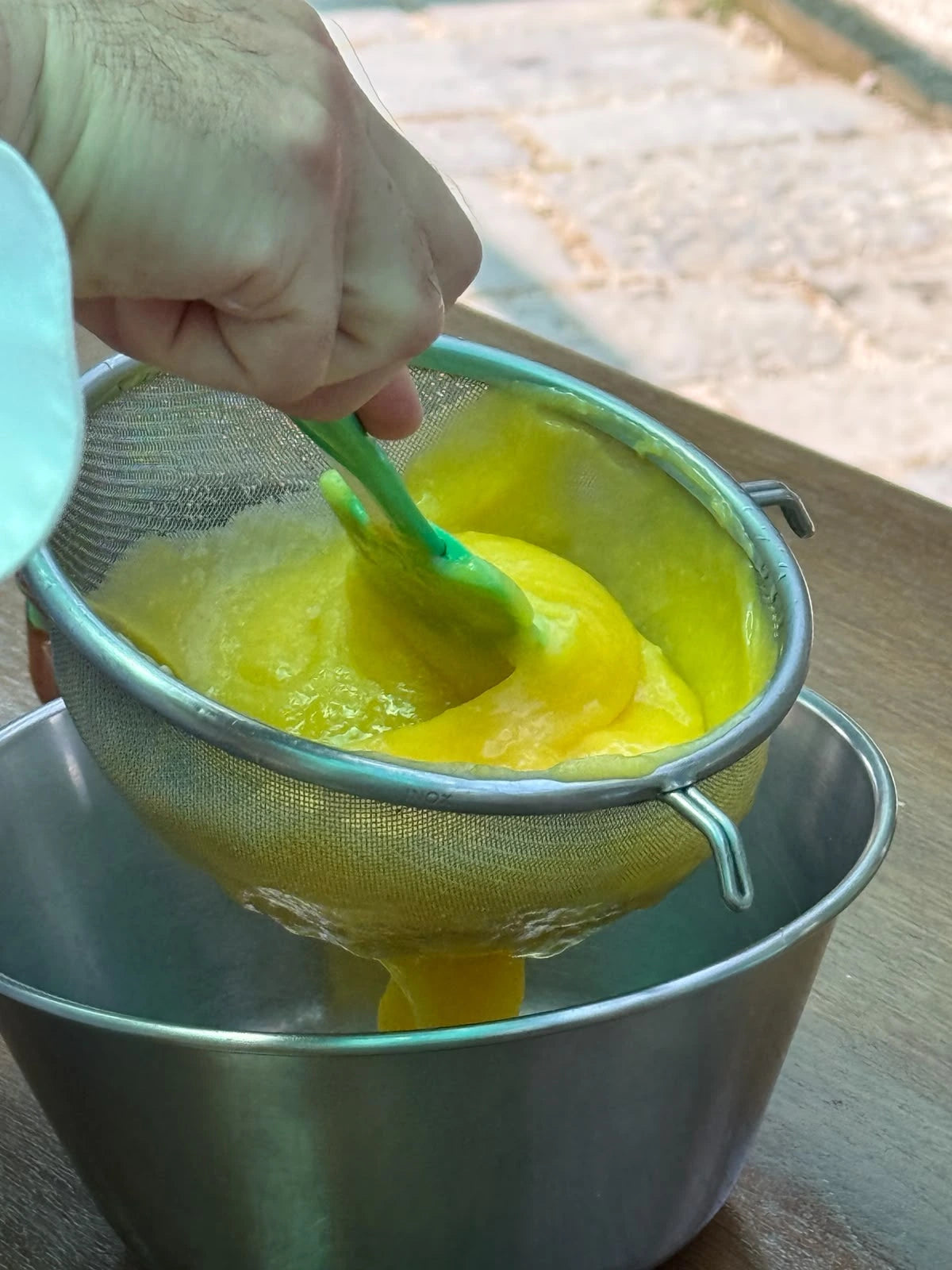 Person straining lemon puree for a gluten free cooking class at a local farm in Sorrento.