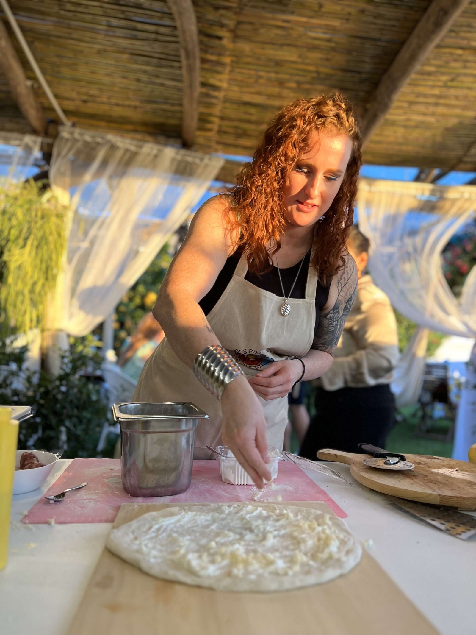 Participant in a Pizza Making Class adding toppings to dough in a lemon grove setting in Sorrento.