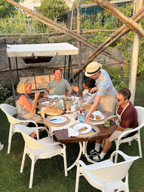 Participants enjoying a private pizza making class in a scenic outdoor setting with sea view.
