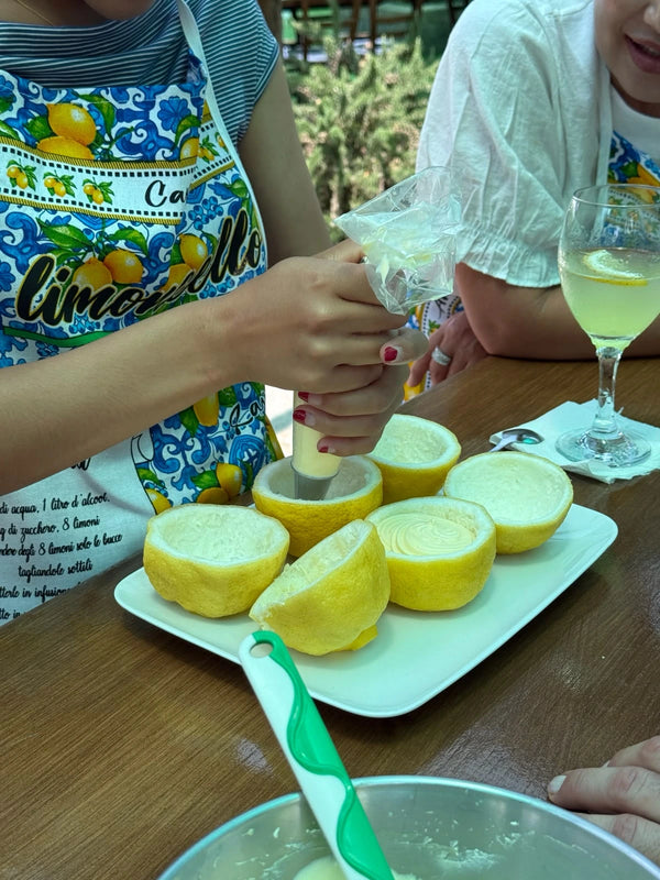 Participants in a gluten free cooking class filling lemon halves with lemon cream on a farm.