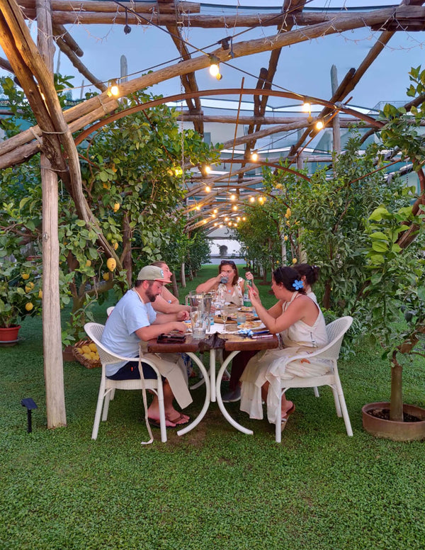 Group enjoying a Pizza Making Class in a seaside lemon grove during sunset in Sorrento.