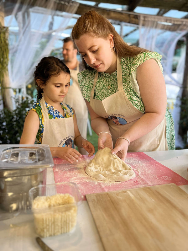 Participants enjoying a Pizza Making Class, shaping dough together in a sunny setting.