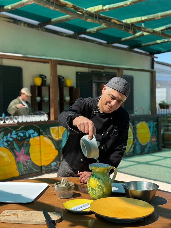 Chef pouring into a decorative pitcher during the Gluten Free Cooking Class Sorrento in a vibrant kitchen.