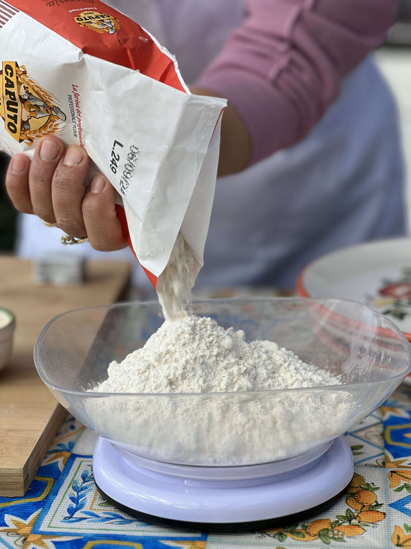 Private pizza making class: pouring flour into a bowl for pizza dough preparation.