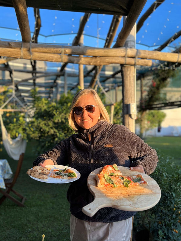 Woman holding pizza and a dish in a lemon grove during a Pizza Making Class in Sorrento.