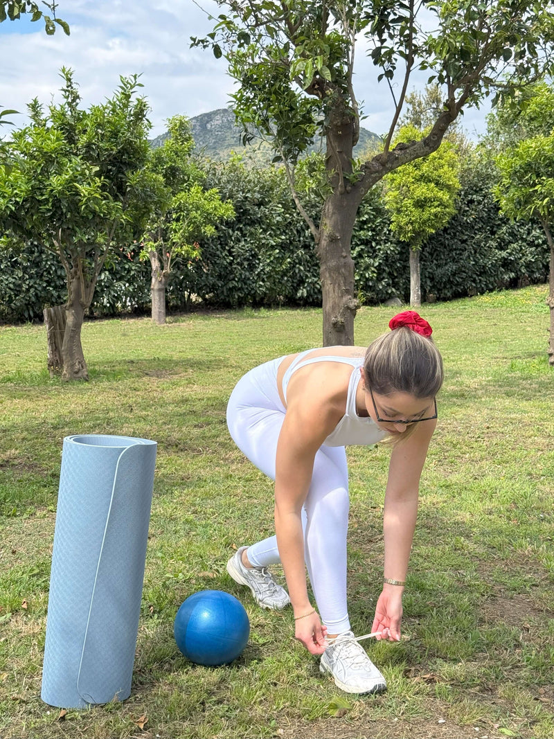 Person tying shoelaces while preparing for Sorrento Pilates Class in a lemon grove.
