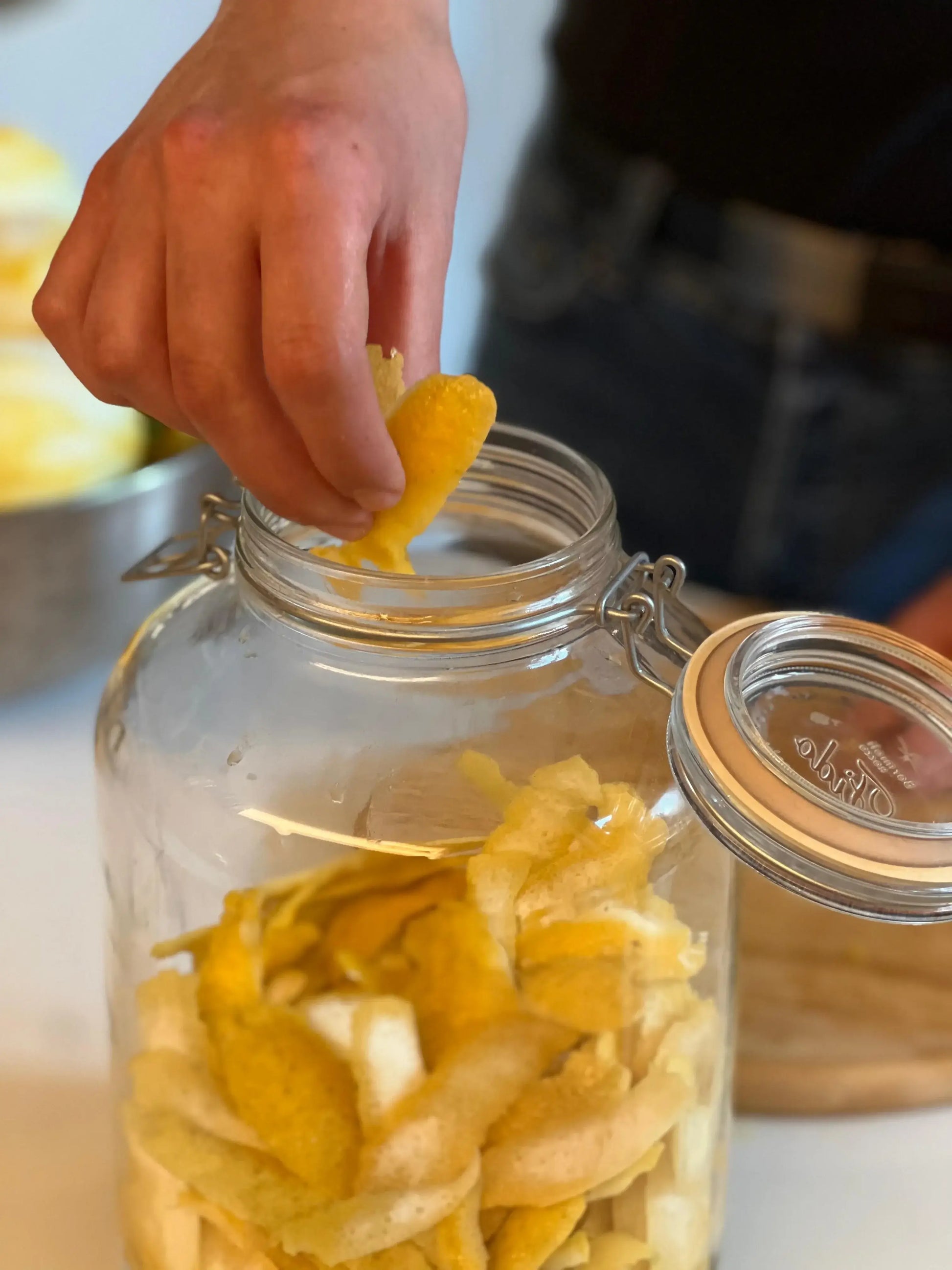 Hand placing lemon peels in jar for crafting homemade Limoncello with Sorrento Lemon Kit.