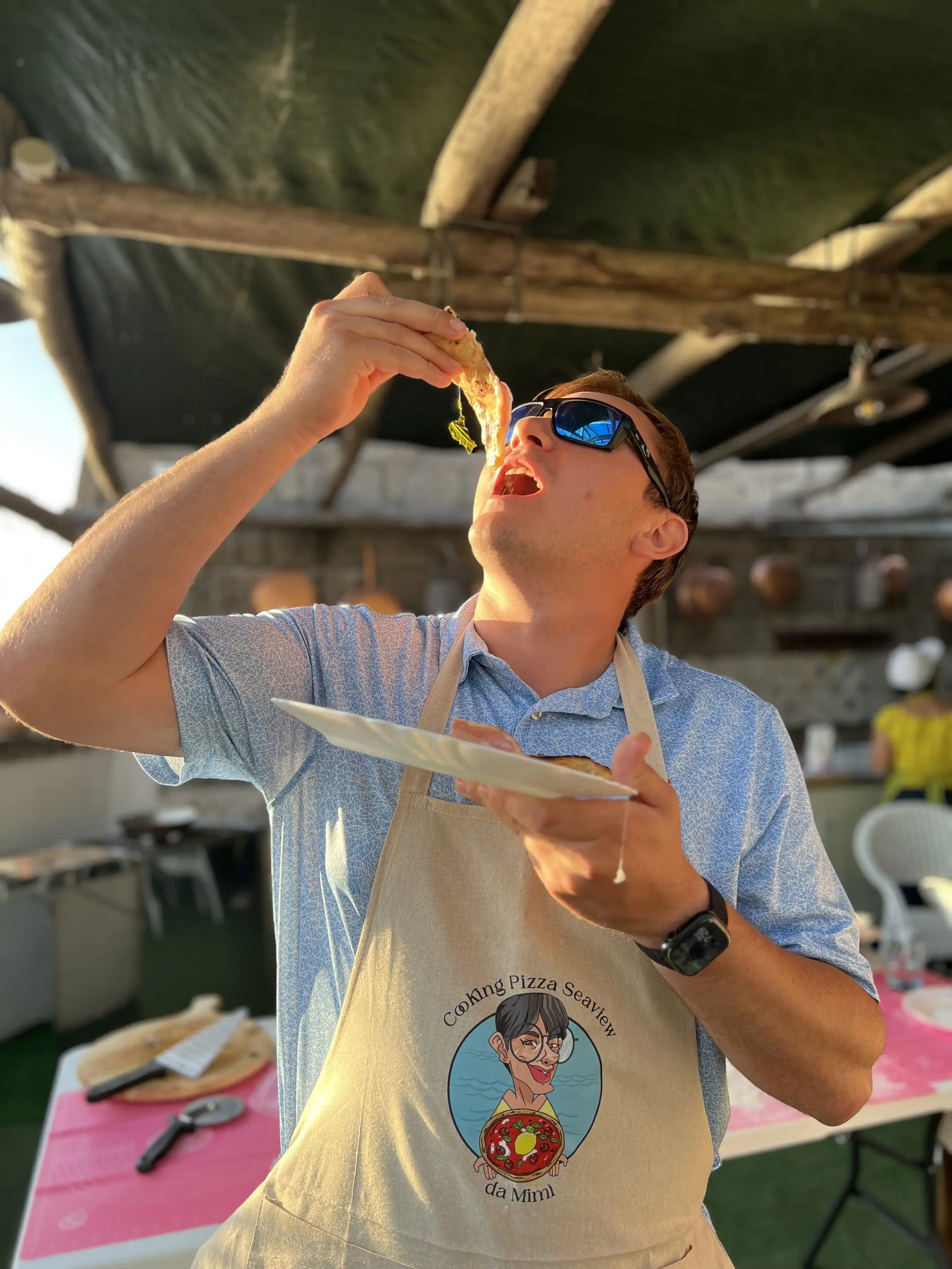 A participant enjoying a slice of pizza during a private pizza making class with sea view.