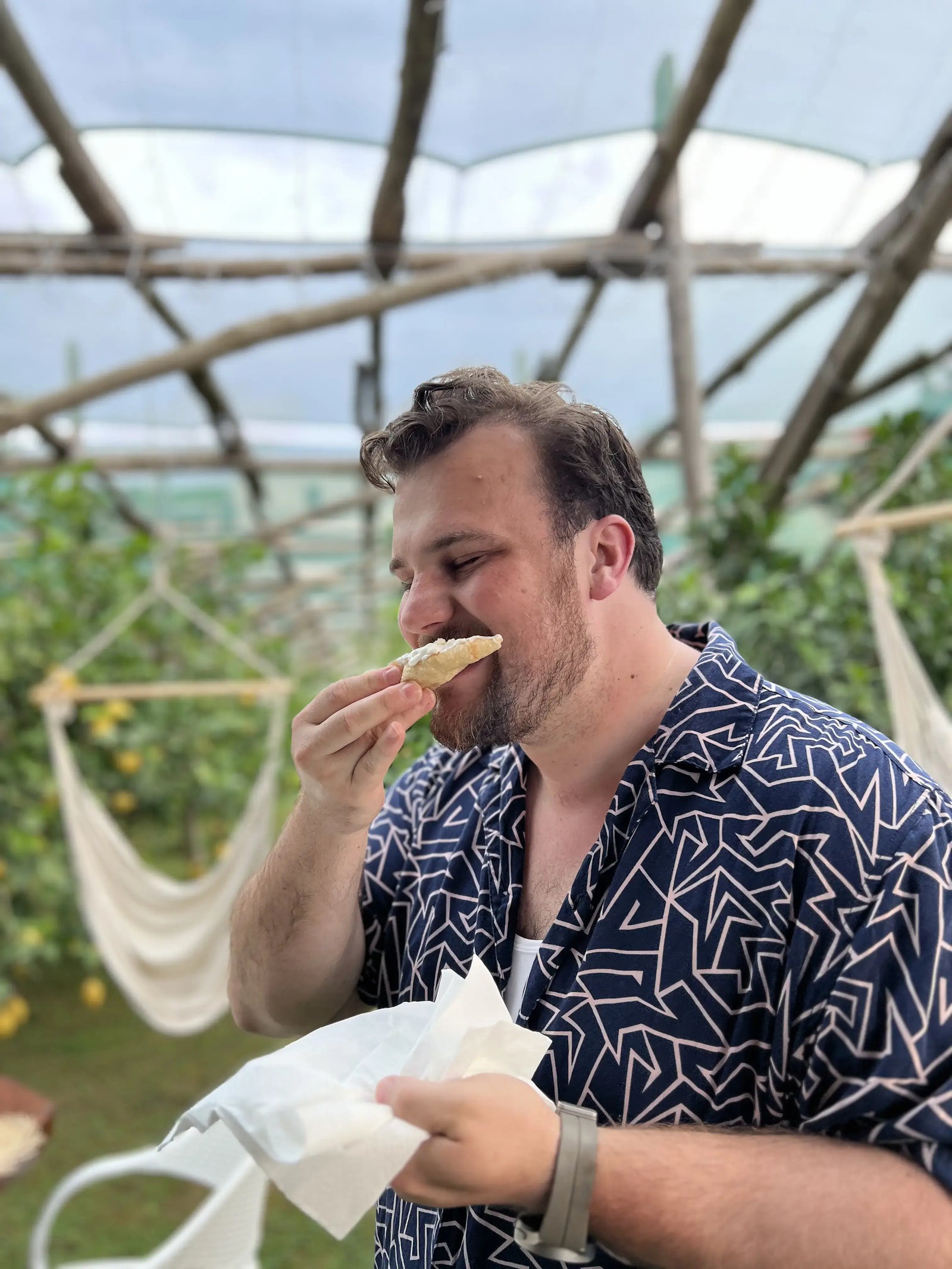 Person enjoying pizza in a seaside lemon grove during a Pizza Making Class in Sorrento.